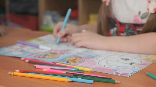 Close-up of unknown child draws the pictures using color pencils in the album in the kindergarten