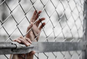 Woman hand holding on chain link fence for remember Human Rights Day concept.