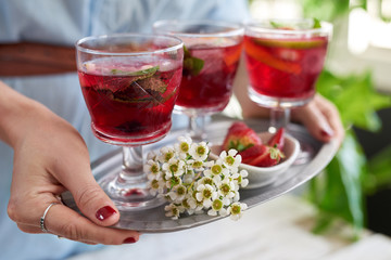 Woman holding tray of berry cocktails at party