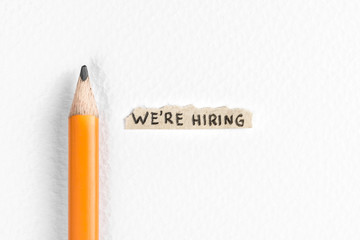 We are hiring message on white textured background and pencil. Job search concept.