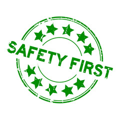 Grunge green safety first wording with star icon round rubber seal stamp on white background