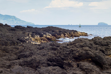 Black volcanic rocks on the ocean background in Bali, Indonesia
