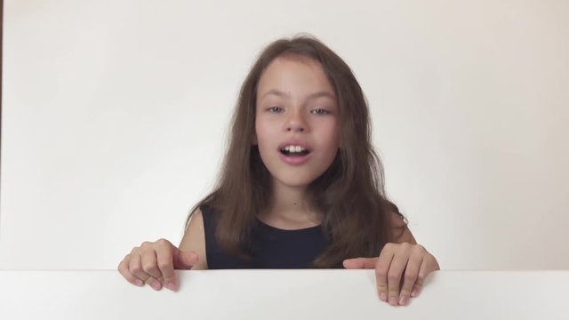 Beautiful girl teenager looks at a poster with information and joyfully advertises it on white background stock footage video.