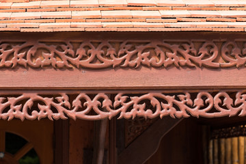 detail of traditional thai house roof style and eave board with wooden shingle and clay tiles