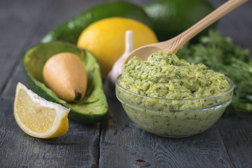 Spoon light wood in the bowl with the avocado cream on rustic table.