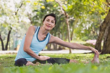 Woman doing yoga pose stretching/meditation at outdoor green park/garden with happy feeling in the morning