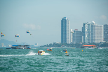 Tourists playing parachute with speed boats running on sea