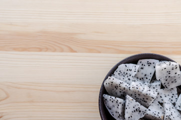 Fresh dragon fruits in black bowl on wooden background.