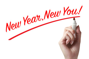 Hand holding a pen and writing new year new you