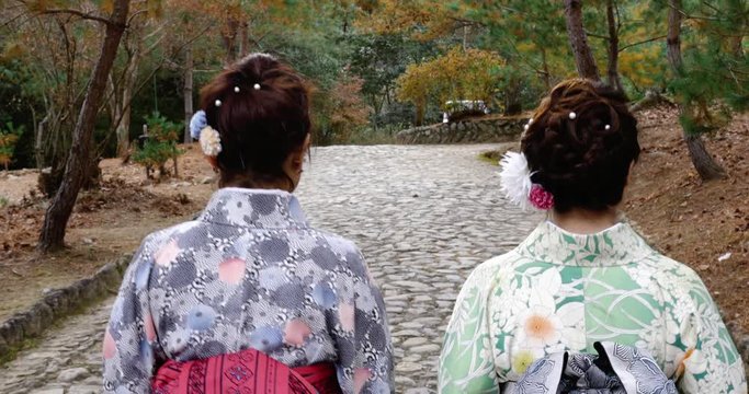 Japanese women in kimonos walking on beautiful stone path.