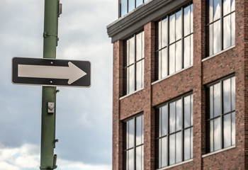 an arrow street sign on a pole in front of a commercial building
