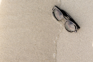 Fototapeta na wymiar Sunglasses on sand beach : Concept summer on holiday