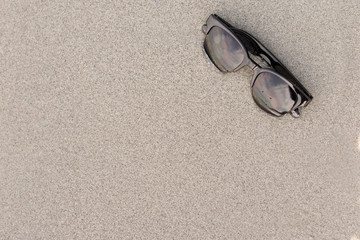 Fototapeta na wymiar Sunglasses on sand beach : Concept summer on holiday