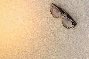 Fototapeta na wymiar Sunglasses on sand beach with sunset. Summer time concept