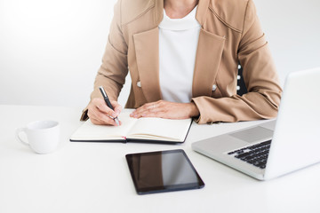 Attractive women in casual business sitting at a table working on her laptop computer at home office in front of a window.