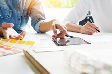 Creative or Interior designers teamwork with pantone swatch and building plans on office desk,...