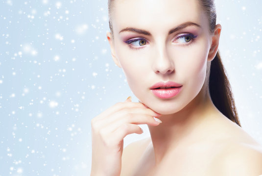 Portrait of young, beautiful and healthy woman: over winter background. Healthcare, spa, makeup and face lifting concept.