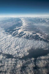 view from the plane to the tops of mountains and clouds