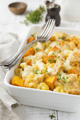 Casserole from chicken meat, pumpkin, pasta ,thyme, cheese and béchamel sauce in ceramic form on light concrete or stone background. Selective focus. Top view. Copy space.