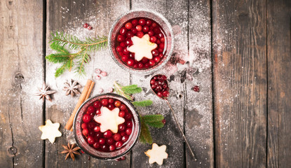 A traditional winter drink of mulled wine from apple berries and spices on a wooden dark background. Celebratory concept. Flat layout. Place for text.