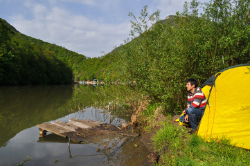 Young man camping by the river and get rest in nature.  Morning on the river