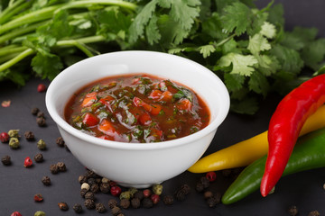 A bowl of red sauce or ketchup, spicy Chilean pepper and ingredients