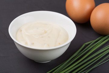 A bowl of white sauce, onions and eggs ingredients