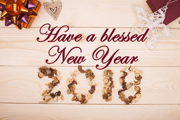 Fototapeta na wymiar Have a Blessed New Year 2018 inscription of dried flowers, orange and burgundy gift boxes, white Christmas-tree toy stars on a light wooden background. Top view. Copyspace.
