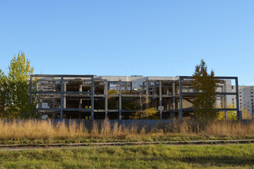Fototapeta premium an abandoned multi-storey building in the middle of a wasteland, the ruins of a modern building