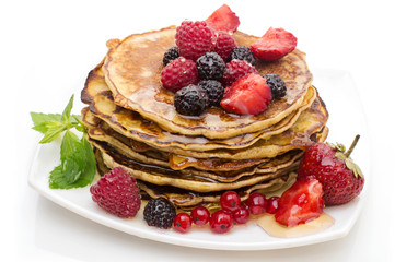 Delicious pancakes with berries and maple syrup on a white background