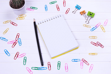 open notebook with blank pages and pen and pensil on white wooden desk