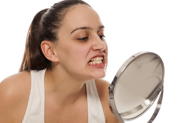young woman checking her teeth in the mirror