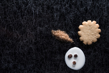 Coffee beans in spilled milk and brown sugar together with a cookie on a black and silver kitchen table top in hard, low key light - 183452517