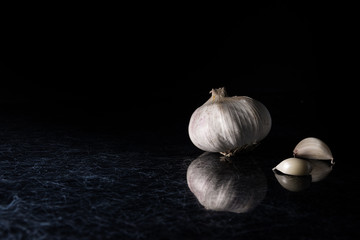A garlic head with garlic cloves on a black and silver kitchen table top - 183452555
