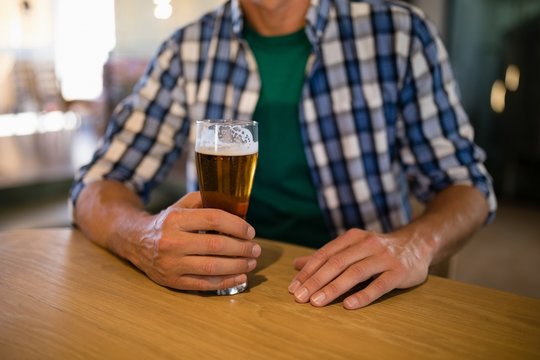 Man sitting with glass of beer at bar counter