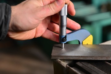 Elderly worker looks in the drawing to see detail sizes. The man turner measures the dimensions of the part on a micrometer, and also uses a sliding caliper.