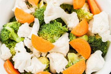 Fresh salad with raw broccoli, cauliflower and carrot in a white dish