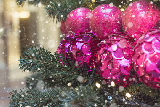 Christmas tree with holiday pink disco balls and lights with copy space on blurred bokeh background in mall. Close up.