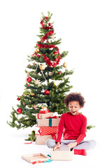 Portrait of cute mixed race little boy unpacking gifts near Christmas tree and taking digital tablet out of box