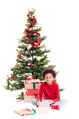 Portrait of cute mixed race little boy unpacking gifts near Christmas tree and taking digital tablet out of box