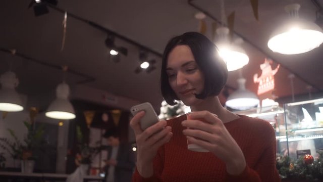 Attractive woman using smartphone taking selfie sitting in cafe. Christmas time