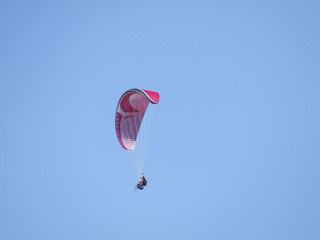Vol en parapente avec aile rouge sur fond de ciel bleu d'été en montagne.