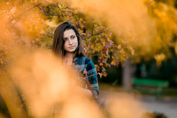 Outdoor atmospheric lifestyle photo of young beautiful lady in autumn park. Brown hair and eyes. Warm autumn. Copy space