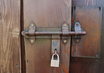 Locked padlock with chain at wooden door background, vintage, Closeup