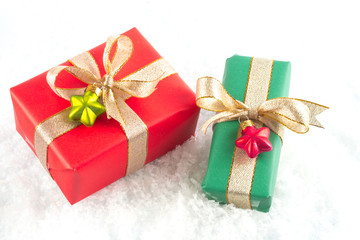 Two Christmas presents packed in red and green wrapping paper on white snowflakes