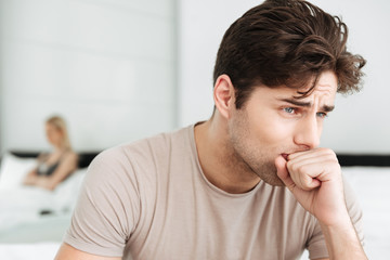 Fototapeta premium Portrait of sad brunette man sitting in bed at home