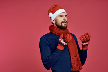 man with a beard, christmas hat, gloves, scarf, emotion, gesture, new year, holiday, christmas, red background