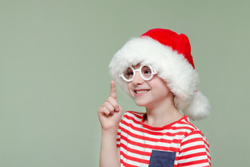 Laughing boy in a santa hat and glasses threatens finger