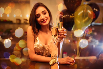 Glamour beautiful  smiling woman with champagne and golden ballons on background in a restaurant selebrating new year, christmas, x-mas