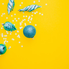 Christmas or New Year composition. Christmas blue balls and silver confetti on yellow background. Flat lay, top view